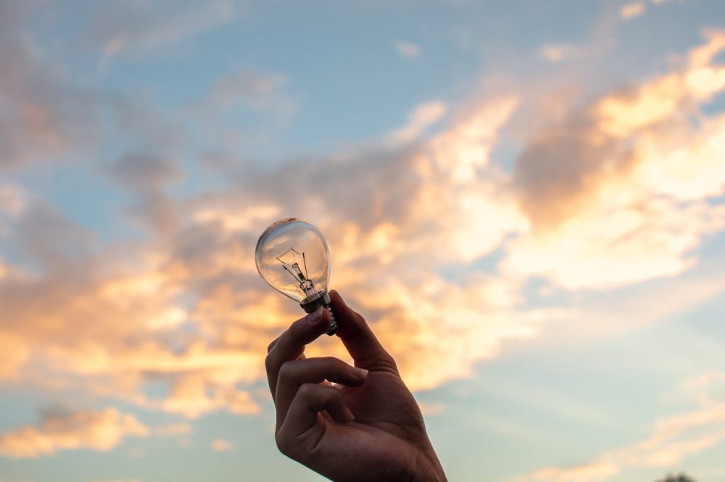 pexels-photo-1314410 A hand holds a light bulb against a scenic sunset sky, symbolizing creativity and innovation.